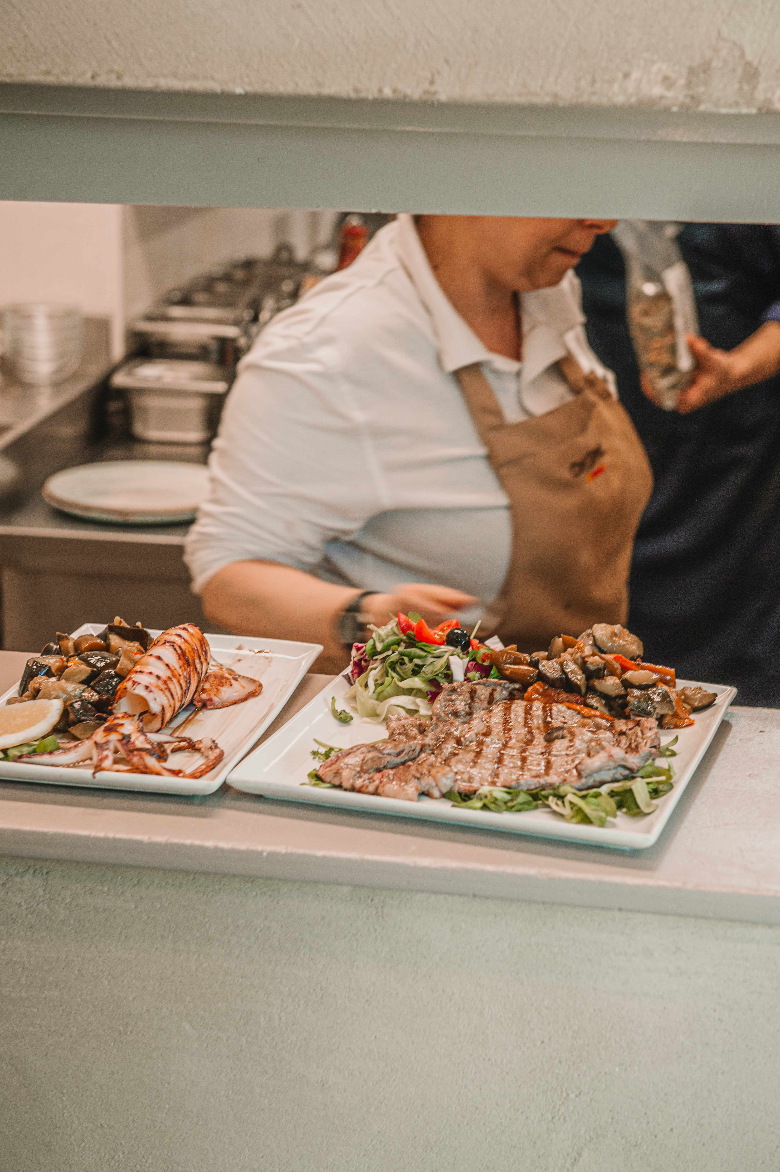 Chef che prepara piatti di carne e pesce in cucina